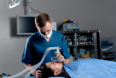 Anesthesiologist making ingalation anesthesia for patient. Doctor puts a mask on the patient before starting operation